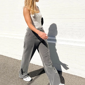 Outdoor view of grey high-waisted wide-leg trousers with elegant drape and side pockets