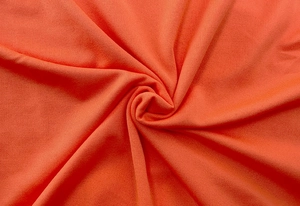 Detailed macro view of orange ribbed knit fabric texture with soft vertical grain