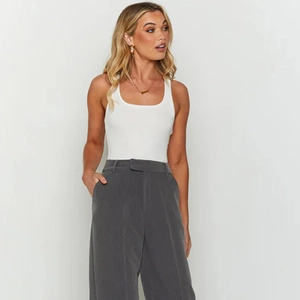 Detailed view of a white U-neck sleeveless bodysuit paired with grey wide-leg trousers