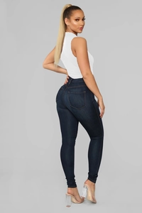 Detail of high-waist skinny jeans with orange stitching and white sleeveless bodysuit