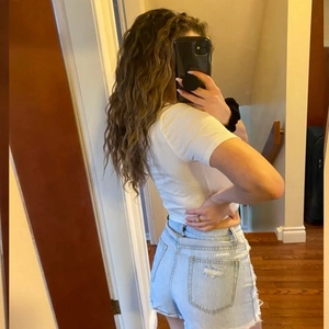 Détail de short en jean taille haute bleu clair avec poches usées et ourlets effilochés