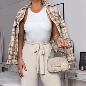 Women's white sleeveless bodysuit paired with plaid shirt and high waist striped pants