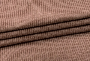 Macro shot of dusty pink ribbed knit fabric showing soft texture and vertical patterns