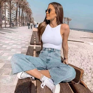 Street style detail of a white halter bodysuit paired with high-waisted wide-leg jeans