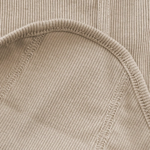 Detail of high-stretch ribbed fabric with precise stitching on a beige camisole