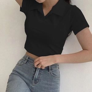 Gros plan d'un crop top polo noir ajusté montrant le col et la texture de la maille
