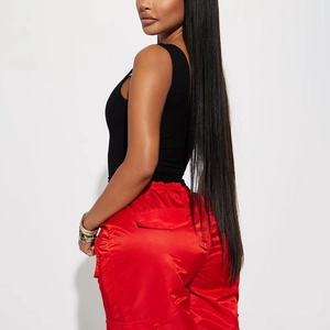 Détail du pantalon cargo en satin rouge porté avec un body noir à col en V