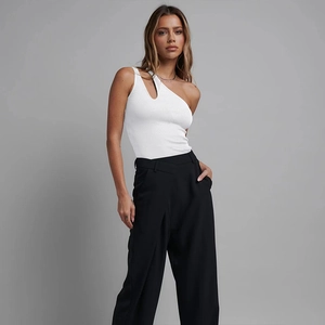 Detail eines weißen One-Shoulder-Bodysuits mit Ausschnitt und schwarzer High-Waist-Hose