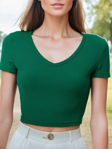 Top corto verde scuro a coste con scollo a V abbinato a pantaloni bianchi a vita alta