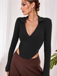 Detail of black ribbed knit bodysuit featuring deep V-neckline and slim fit long sleeves
