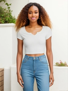 Dettaglio del crop top bianco a coste in cotone con scollo a V e vestibilità slim