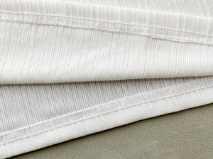 Detaillierte Nahaufnahme von weißem Rippstrickstoff mit hochwertiger Overlock-Naht