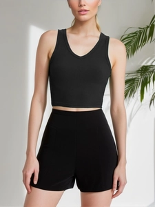 Close-up of black ribbed tank top and high waist shorts set on a model in a minimalist room