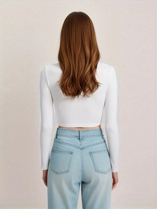 Back view of a white long-sleeve crop top in ribbed knit fabric paired with denim jeans