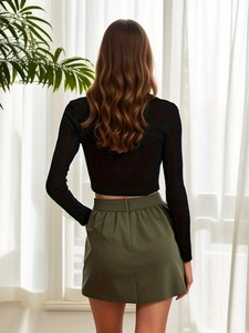 Rear view of woman in black ribbed crop top and olive green high waisted mini skirt