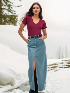 Detail of burgundy ribbed V-neck bodysuit paired with a high-slit light blue denim skirt