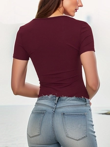 Detail of ribbed fabric texture on deep wine red bodysuit and frayed denim jeans hem