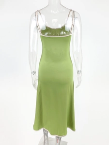 Detailed back view of green satin dress featuring white contrast piping and slim straps