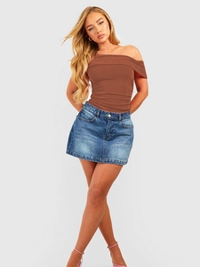 Detail of slim fit brown off-shoulder bodysuit paired with classic denim mini skirt