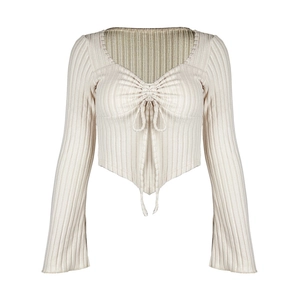 Detail of cream rib-knit top featuring deep V-neckline and adjustable drawstring ruching