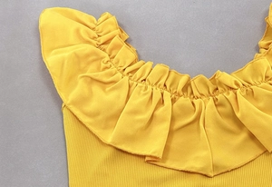 Detailed close-up of ginger yellow ribbed fabric with ruffled off-the-shoulder neckline