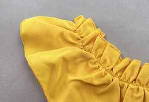 Detail of elegant bright yellow ruffled neckline with fine pleated chiffon fabric texture