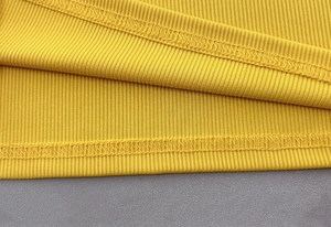 Detail of fine double-stitching and ribbed texture on the bright yellow knit top