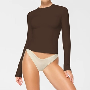 Detail of the high-stretch fabric and slim fit on this dark brown long sleeve crewneck top