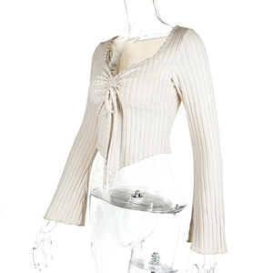 Macro view of apricot V-neck knit top showing ribbed texture and drawstring ruching details