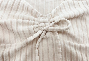 Detail of cream rib-knit fabric featuring a drawstring bow and vertical texture