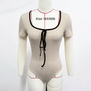 Détail d'un bodysuit en maille côtelée abricot avec bordure noire et laçage à l'avant