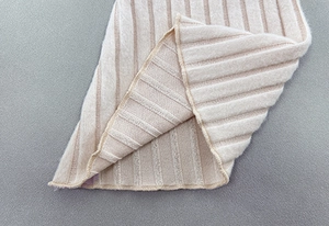 Macro detail of beige ribbed knit fabric showing vertical texture and high-quality stitching