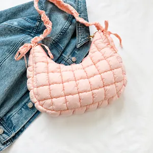 Pink quilted hobo shoulder bag with ruffled strap and decorative bow detail close-up