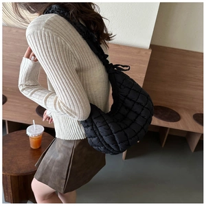 Detailed view of black quilted puffer shoulder bag with a soft texture on model