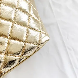 Macro detail of quilted diamond pattern on gold metallic textured tote bag surface