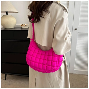 Detailed view of hot pink quilted hobo shoulder bag styled with a beige trench coat