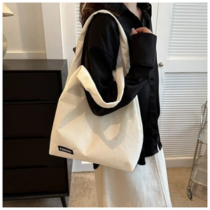 Gros plan d'un sac cabas en velours côtelé crème montrant la texture et l'étiquette