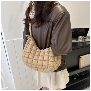 Detailed close-up of a beige quilted puffer bag with chic lattice stitch design