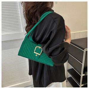 Dettaglio di una borsa a spalla in feltro verde smeraldo con grande fibbia dorata su modella