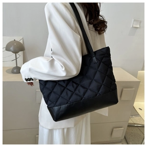 Black quilted tote bag with diamond stitching shown on a model in a stylish setting
