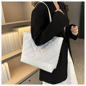Close-up of white quilted tote bag with diamond stitching and leather reinforced bottom