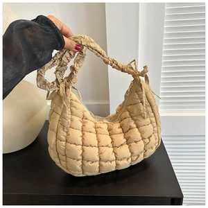 Detail of beige quilted hobo bag featuring pleated strap with decorative bow tie