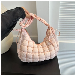 Detail of light pink quilted shoulder bag featuring bow accents and ruffled cloud handle
