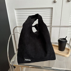 Grand sac cabas en velours côtelé noir avec étiquette mode sur étagère blanche