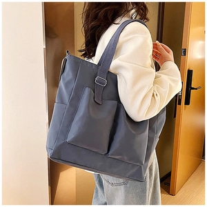 Detail of adjustable strap and front utility pockets on the large grey-blue tote bag
