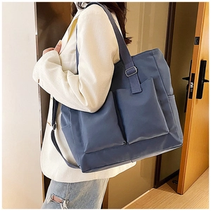 Detail of blue canvas tote bag with large front pockets and adjustable strap for daily use