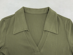 Detail of deep green ribbed knit polo shirt featuring a V-neckline and polo collar design