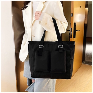 Detail of black multi-pocket canvas tote bag showing side pocket and metal ring hardware