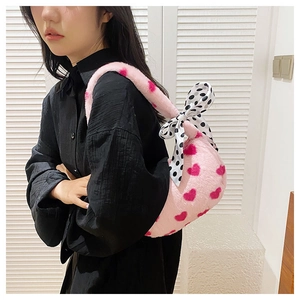 Detail view of pink plush bag with red heart pattern and a black polka dot bow accessory