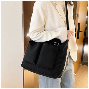Detail of black canvas crossbody bag showing functional pockets and metal buckle strap